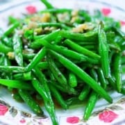 garlic green beans on a white bowl with pink flowers