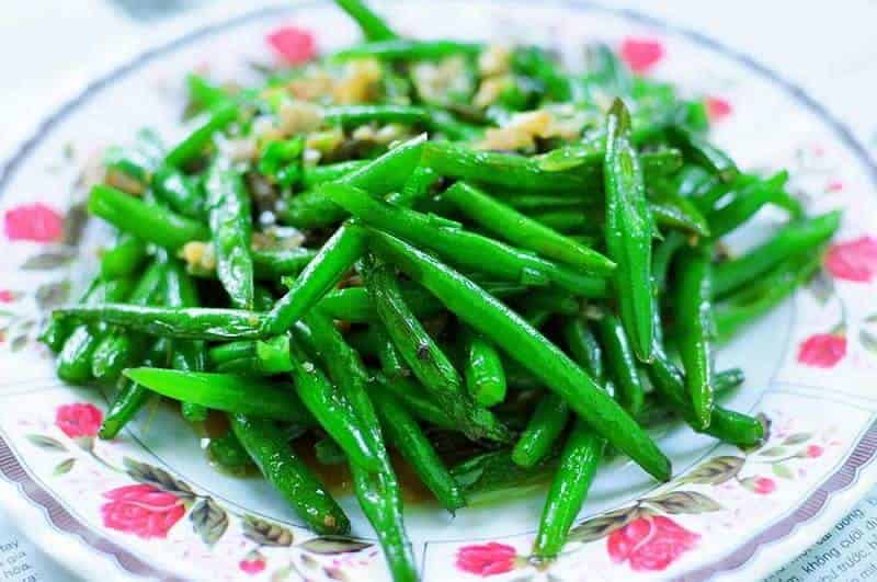 Garlic green beans on a white bowl with pink flowers