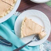 low carb pumpkin cheesecake recipe on a plate with a blue background with a fork with a bite of the cheesecake on it