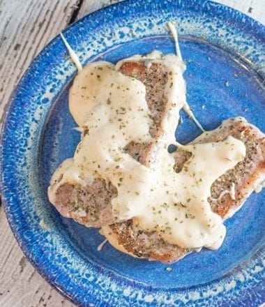 Two low carb pork chops on a blue plate on a white wood background.