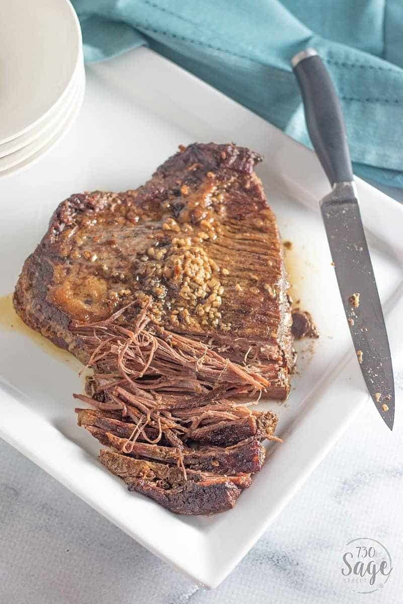 Keto Beef Brisket Korean Style 1 Partially shredded low carb korean beef on a white plate with a knife on the side