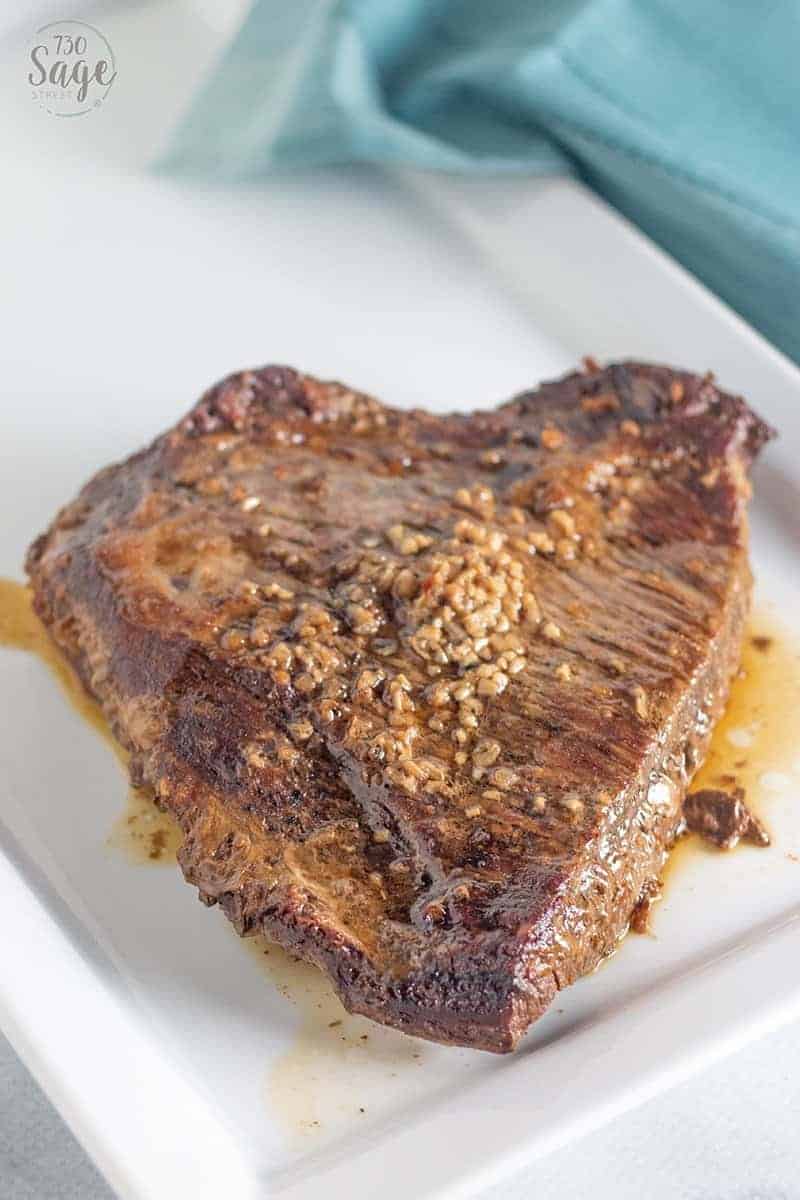 Whole beef brisket slow cooker on a white plate with blue background