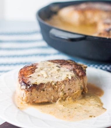 keto pork chops on a white plate with a cream sauce over it