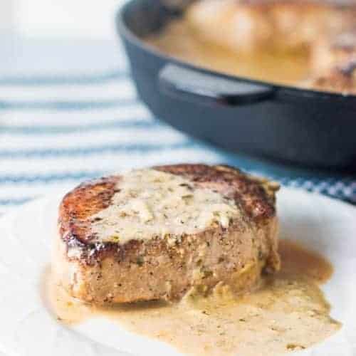 keto pork chops on a white plate with a cream sauce over it