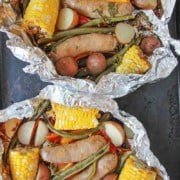 hobo dinner sausage and veggies in foil on a sheet pan