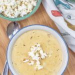 beer cheese soup in a white and blue bowl on a wooden board