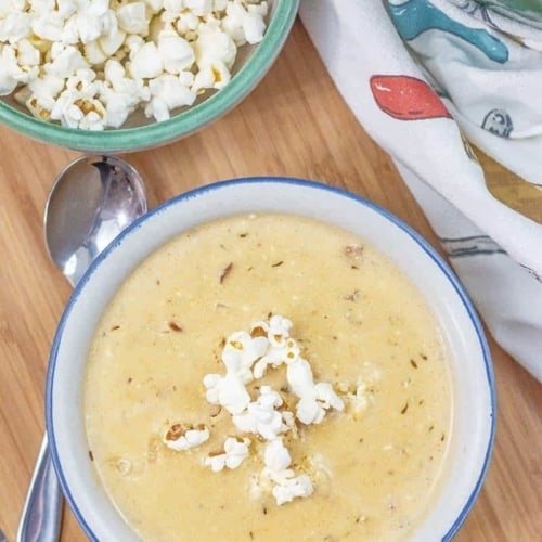 beer cheese soup in a white and blue bowl on a wooden board