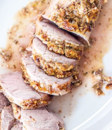 close up of cooked, sliced pork tenderloin on a white plate