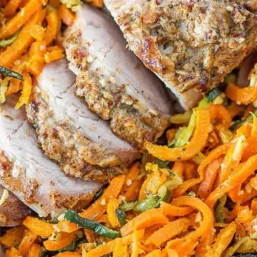 close up of a pork tenderloin sitting on a bed of spiral carrots