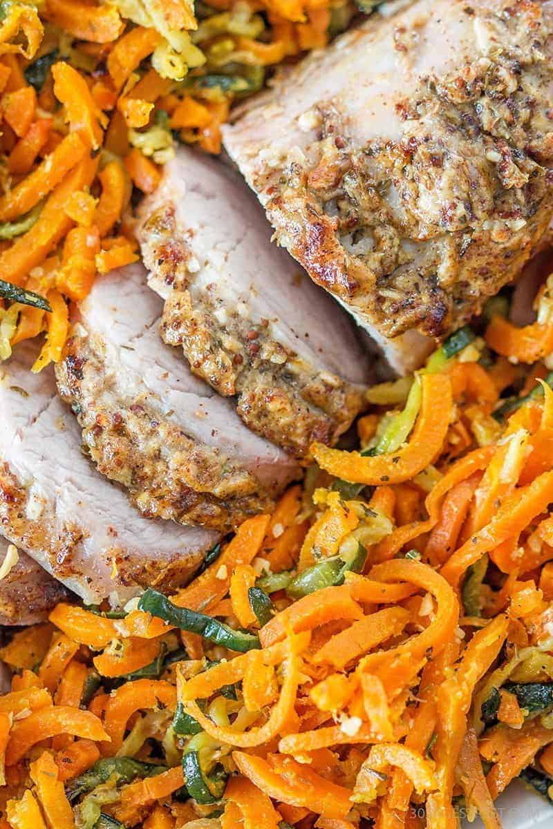 Low Carb Parmesan Dijon Pork Tenderloin with Garlic herb Veggie Spirals close up of a pork tenderloin sitting on a bed of spiral carrots