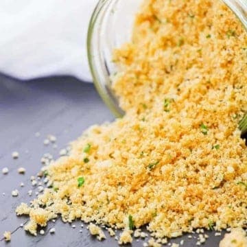 breadcrumbs spilling on a grey background in a glass jar