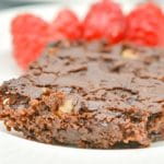 close up of keto brownies on a white plate with raspberries