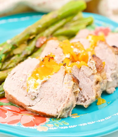 stuffed pork tenderloin on a blue plate with a side of asparagus