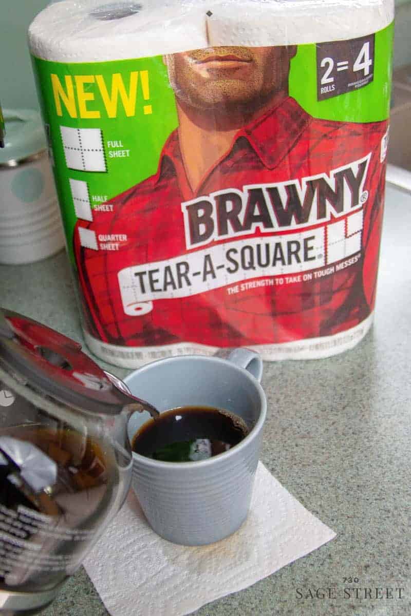 coffee pot pouring a cup of coffee with a package of Brawny paper towels in the background