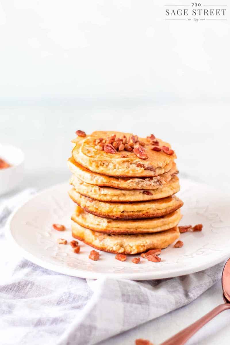 keto pancakes made with ricotta cheese on a white plate sprinkled with pecans view from the side