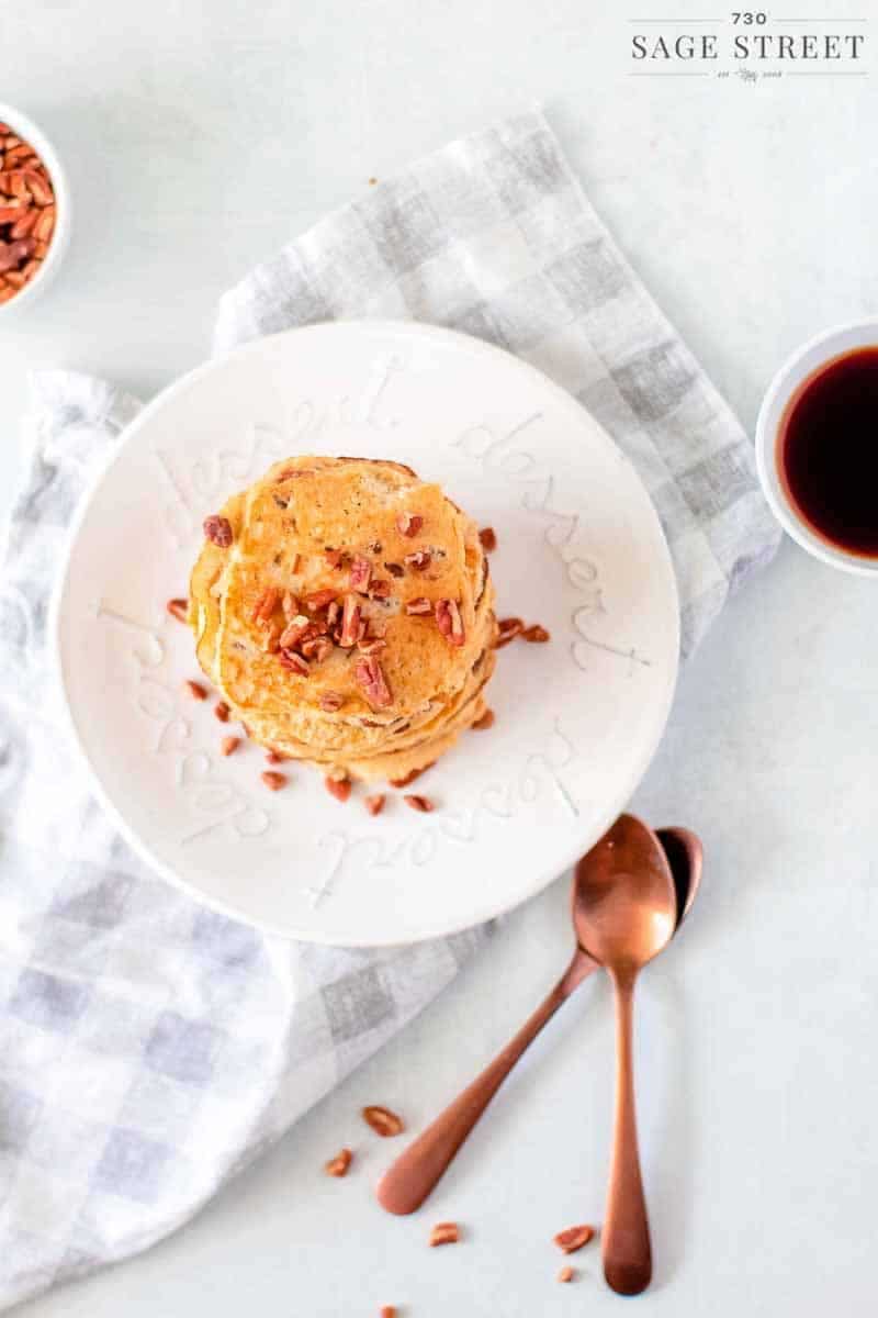 looking down on keto pancakes made with ricotta cheese on a white plate sprinkled with pecans