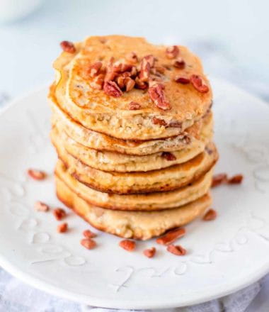 side view of keto pancakes made with ricotta cheese on a white plate sprinkled with pecans