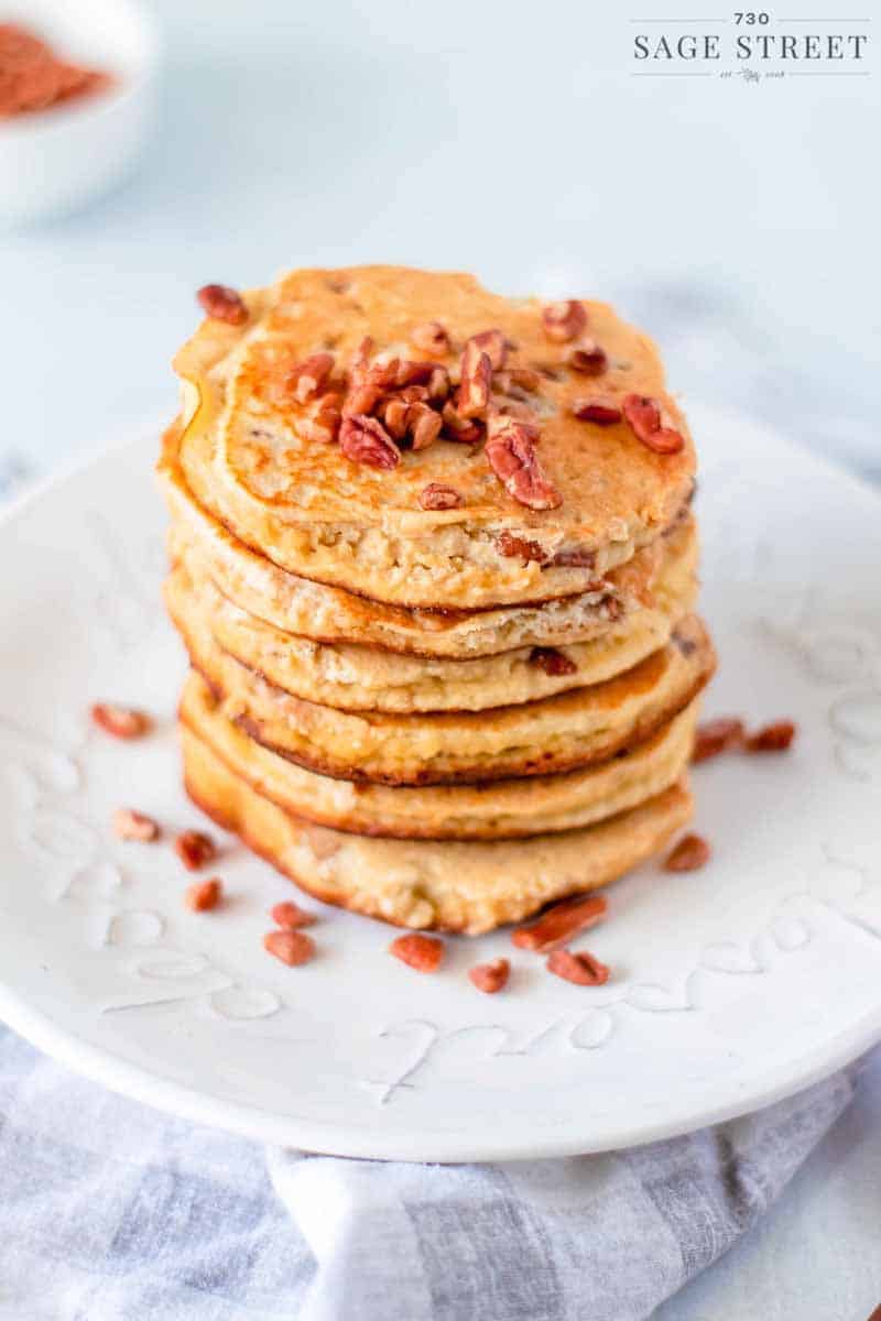 side view of keto pancakes made with ricotta cheese on a white plate sprinkled with pecans