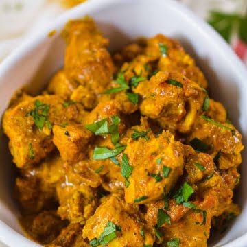 White bowl, with butter chicken and cilantro garnish.