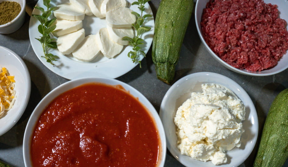 Keto Lasagna ingredients include: oregano, mozzarella, zucchini, ground beef, shredded cheese, crushed tomatoes, and ricotta cheese