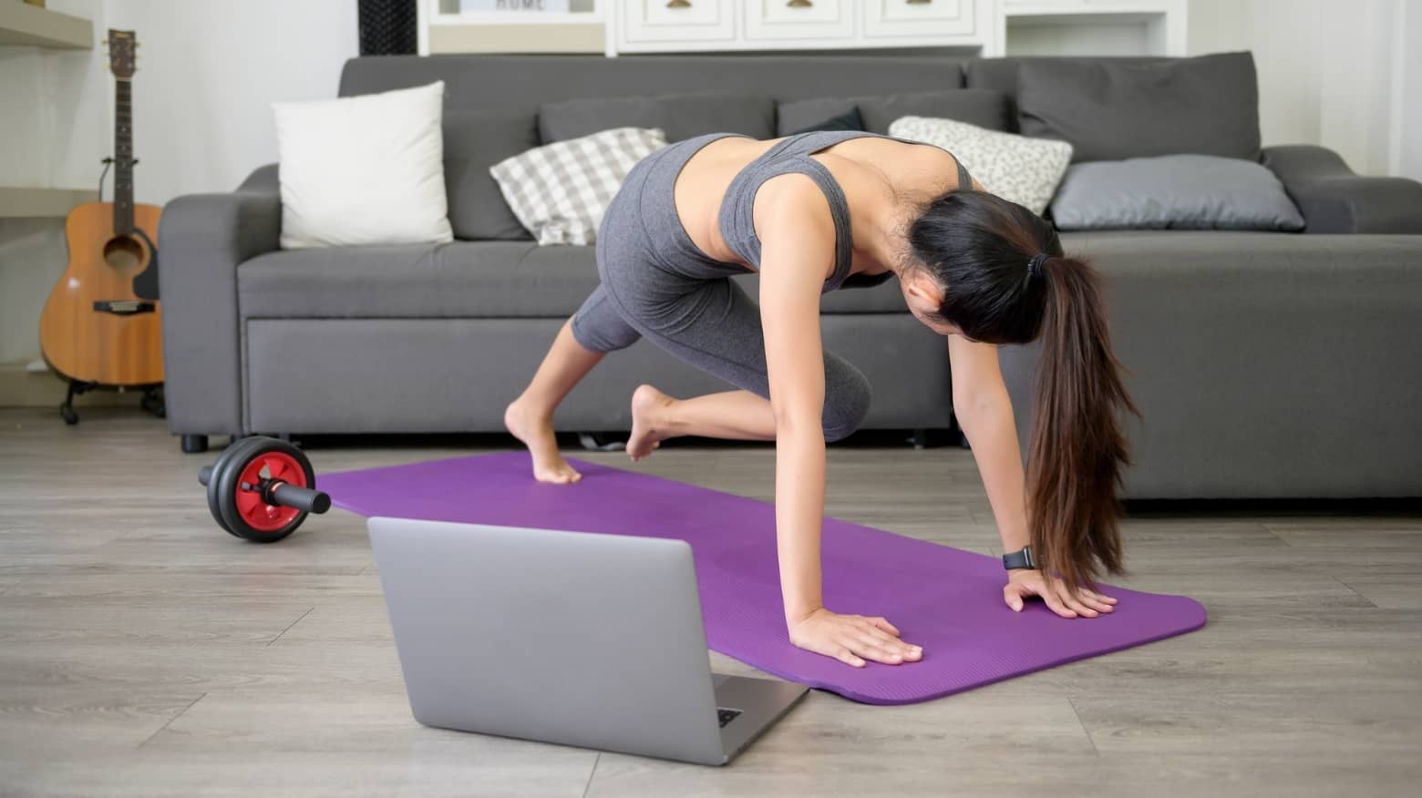 Young woman in fitness outfit doing a set of mountain climbers on her yoga matt