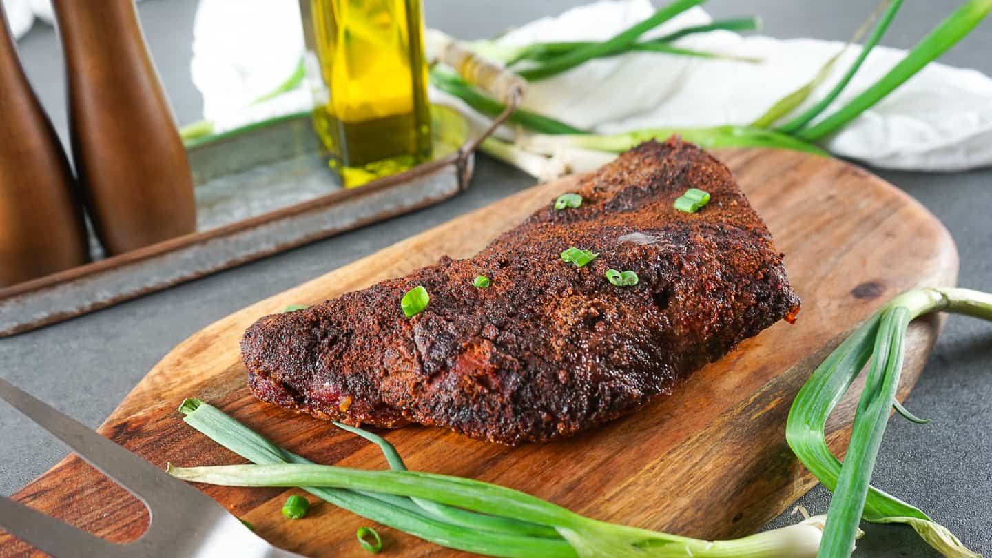 Smoked tri-tip resting on wood cutting board. Beautify bark and amazing aroma.