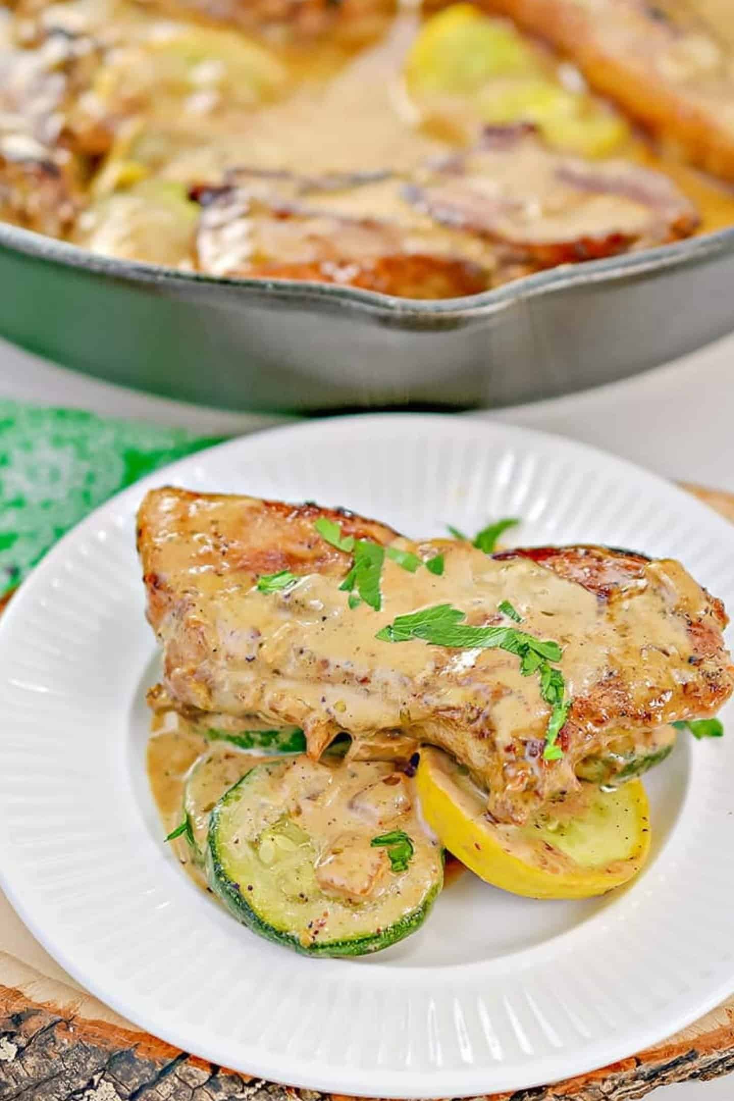 pan seared thin pork chops on white plate covered in creamy mustard sauce