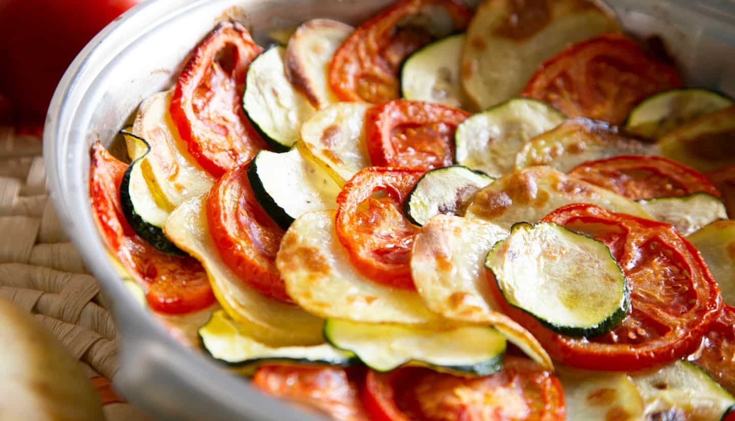 Zucchini tomatoes and potatoes with cheese on a pan
