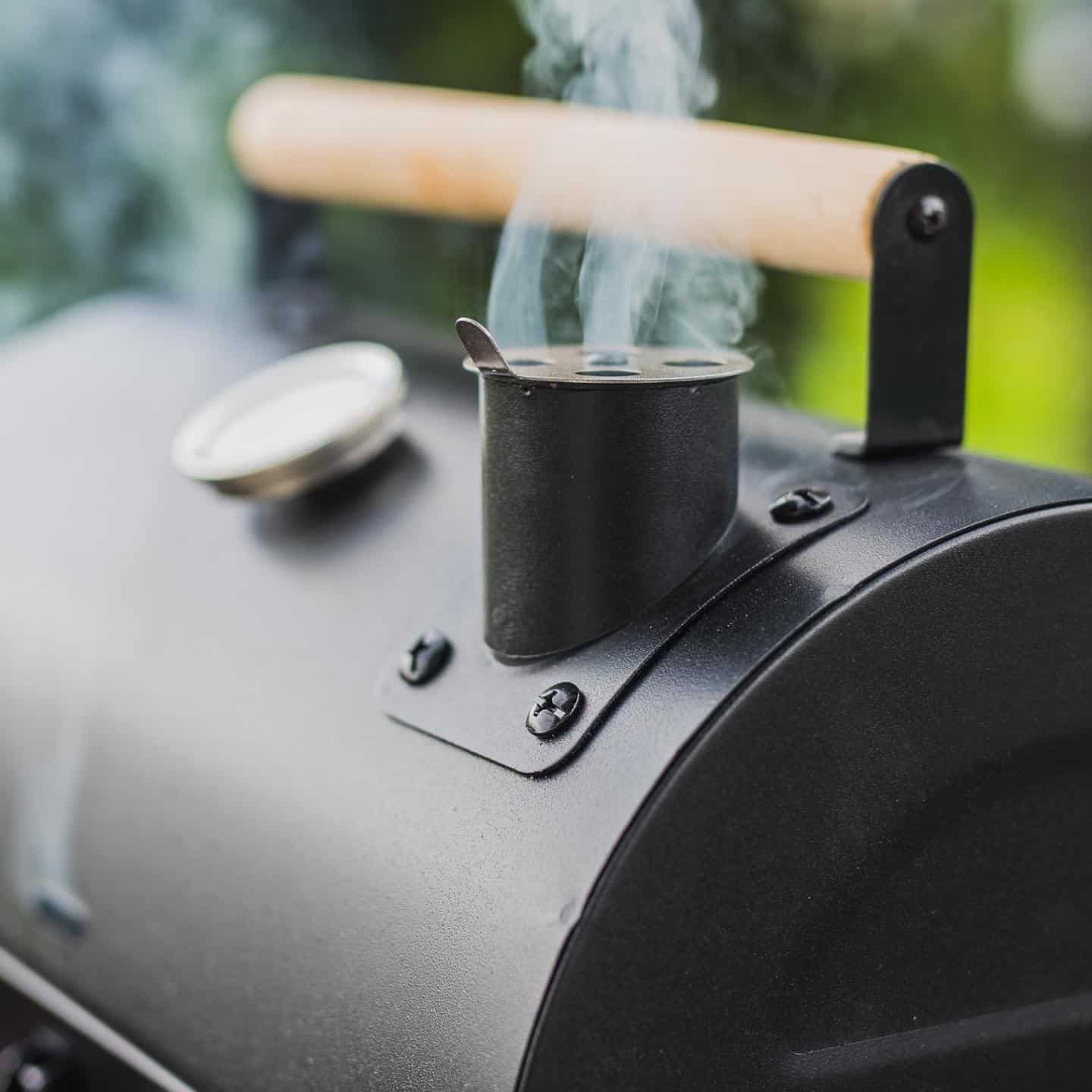 Pellet smoker with steady stream of smoke flowing from the bbq's stack.