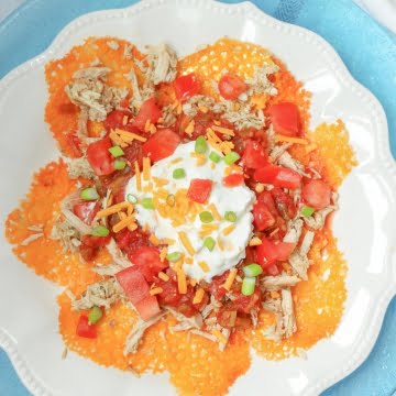 shredded chicken nachos with tomatoes and sour cream on top