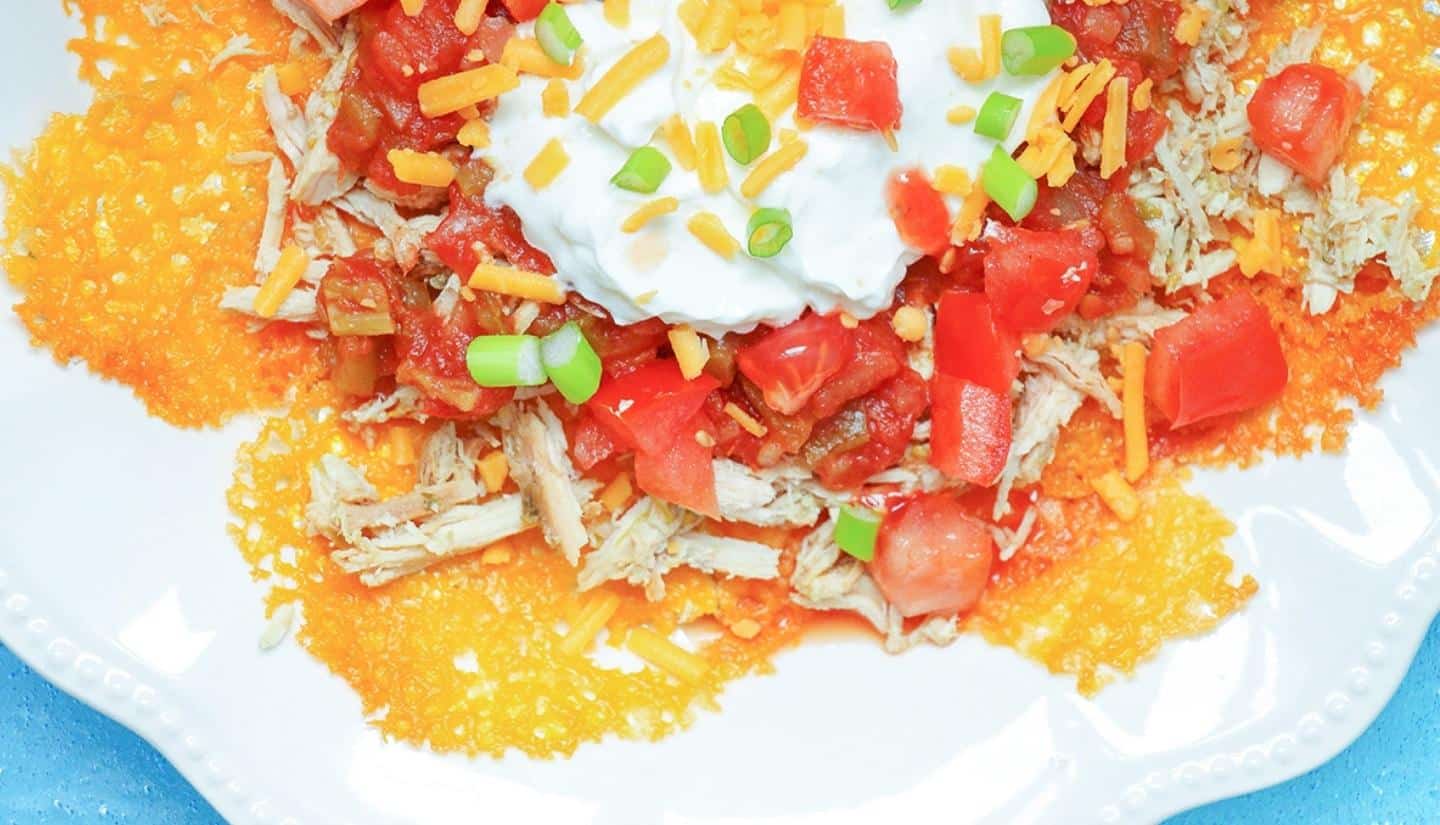 shredded chicken nachos with tomatoes and sour cream on top