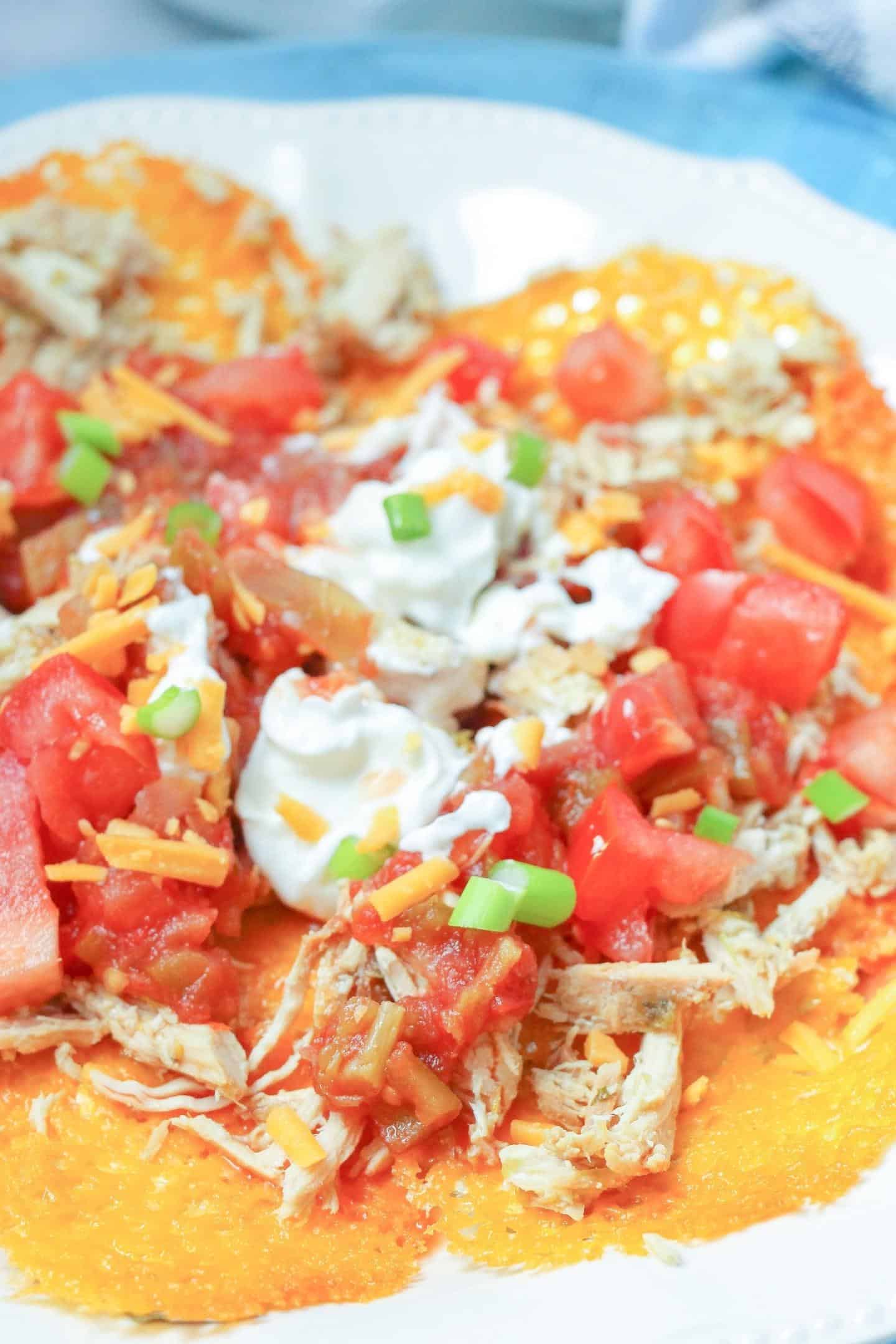 shredded chicken nachos with tomatoes and sour cream on top