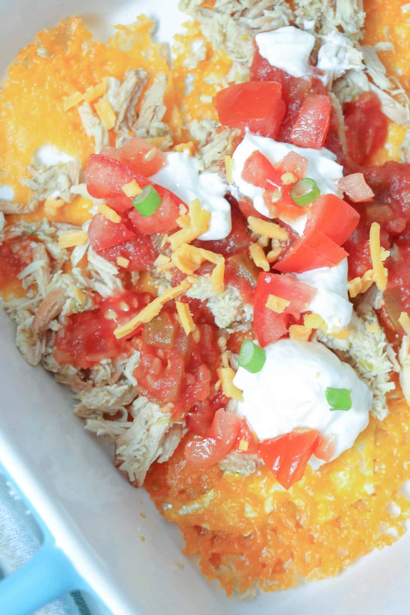 shredded chicken nachos with tomatoes and sour cream on top