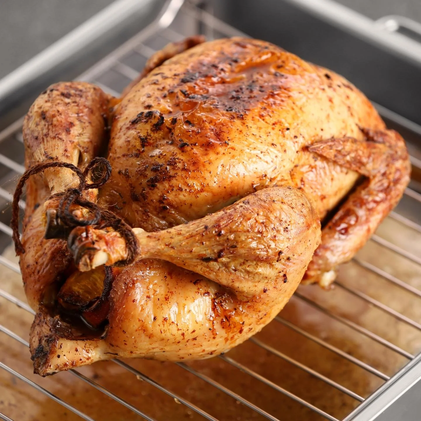 Low and slow turkey sitting on wire rack for improved air circulation. Dripping visible in the roasting pan.