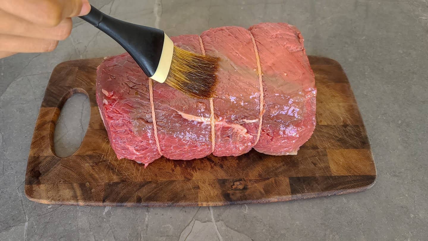 Brushing the bottom round roast with olive oil.