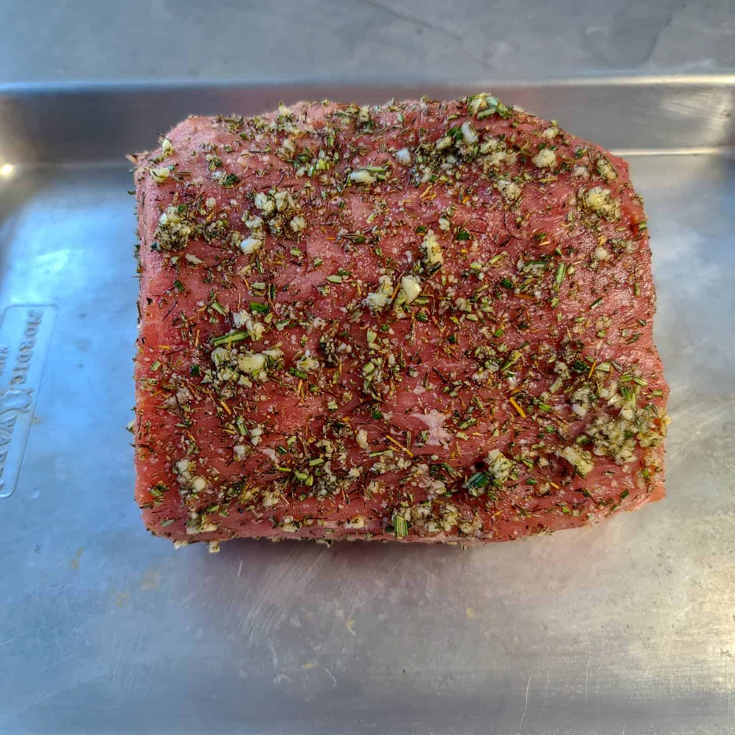 Seasoned eye of round roast in center of Nordic Ware half baking sheet.