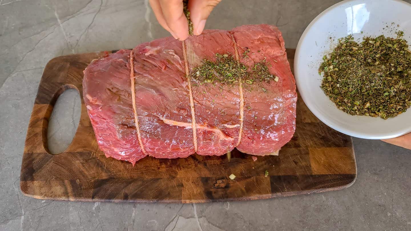 Add seasoning to the bottom round roast and rub or roll to ensure seasoning sticks.