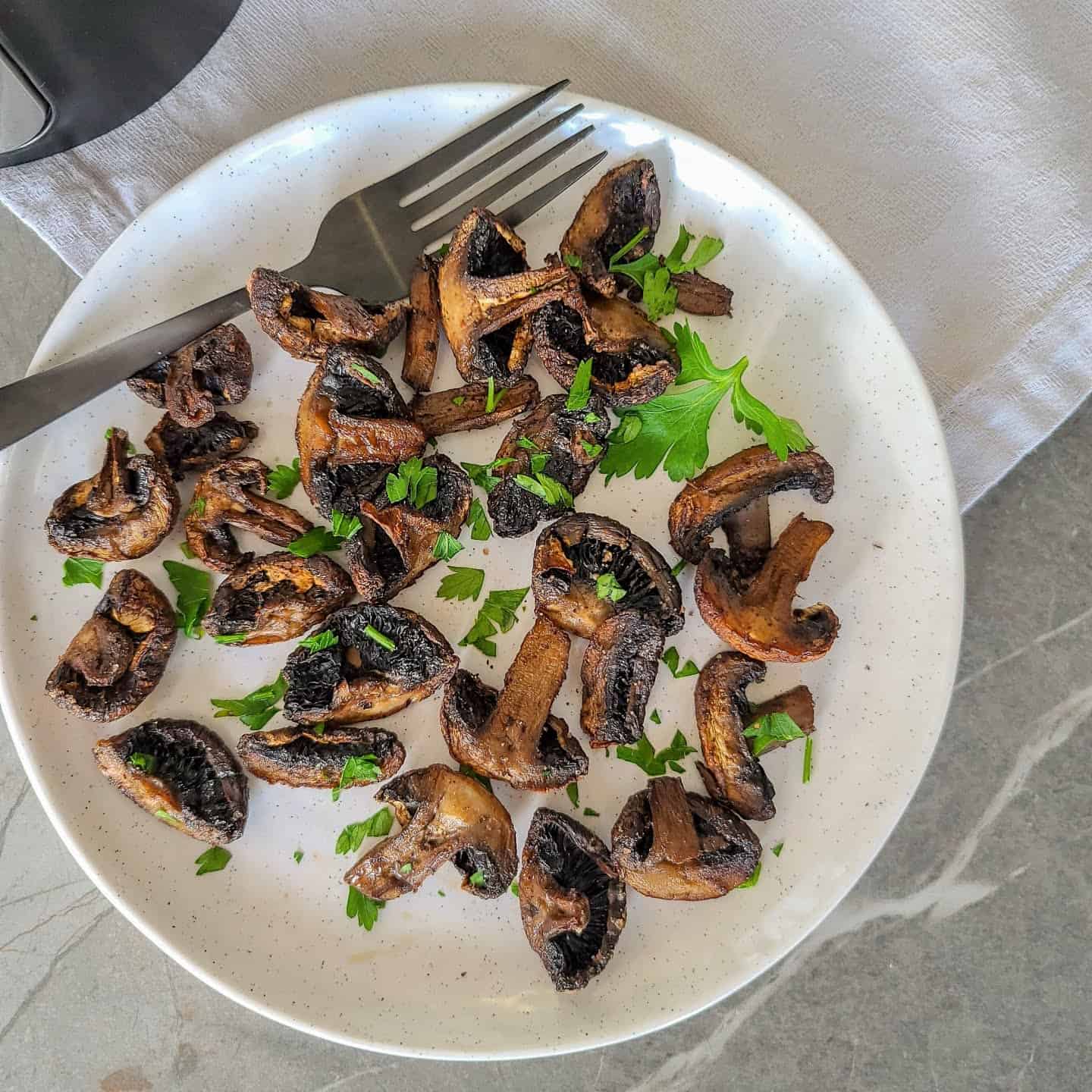 air fried mushrooms served in a plate with parsley garnish