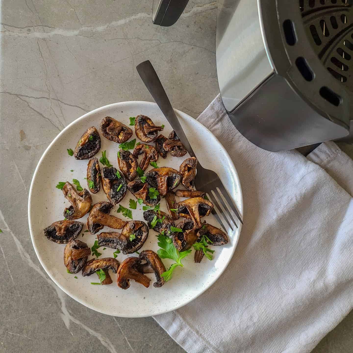 air fried mushrooms served in a plate with parsley garnish