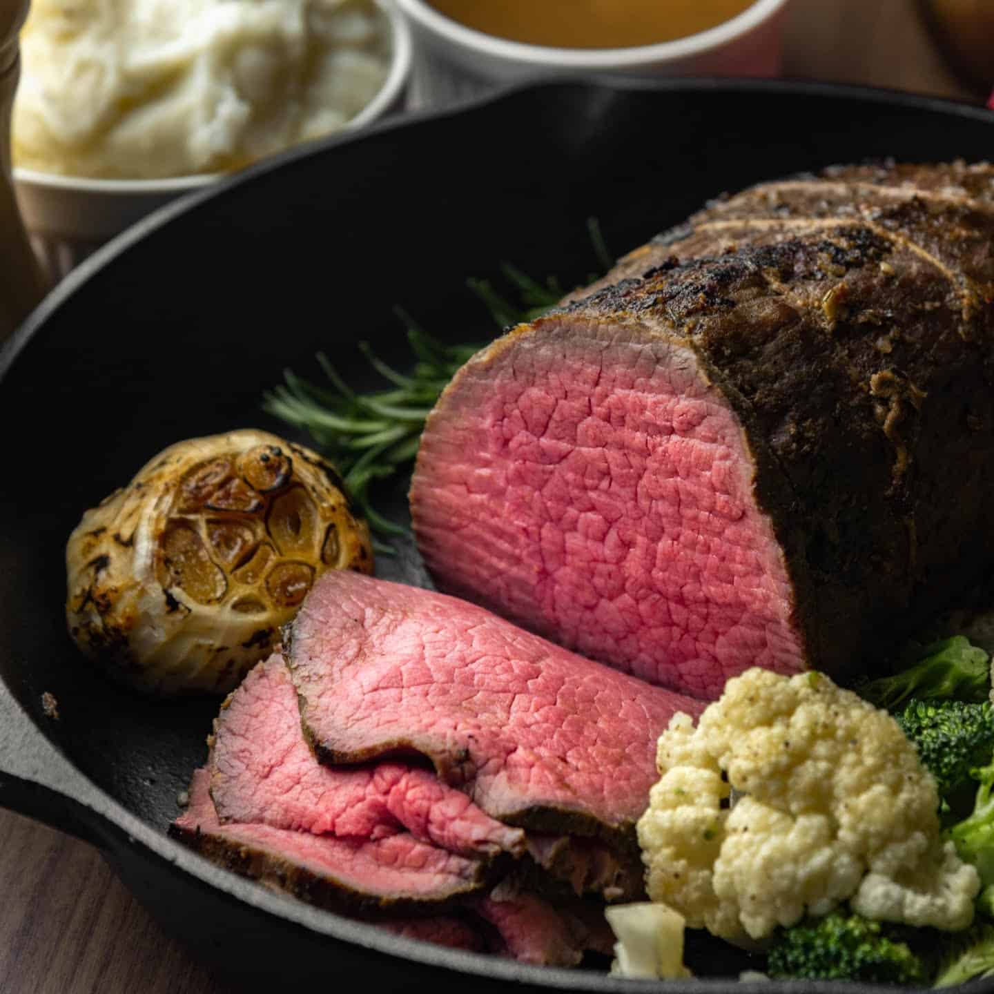 Eye of round roast thinly sliced with roasted garlic and vegetables.
