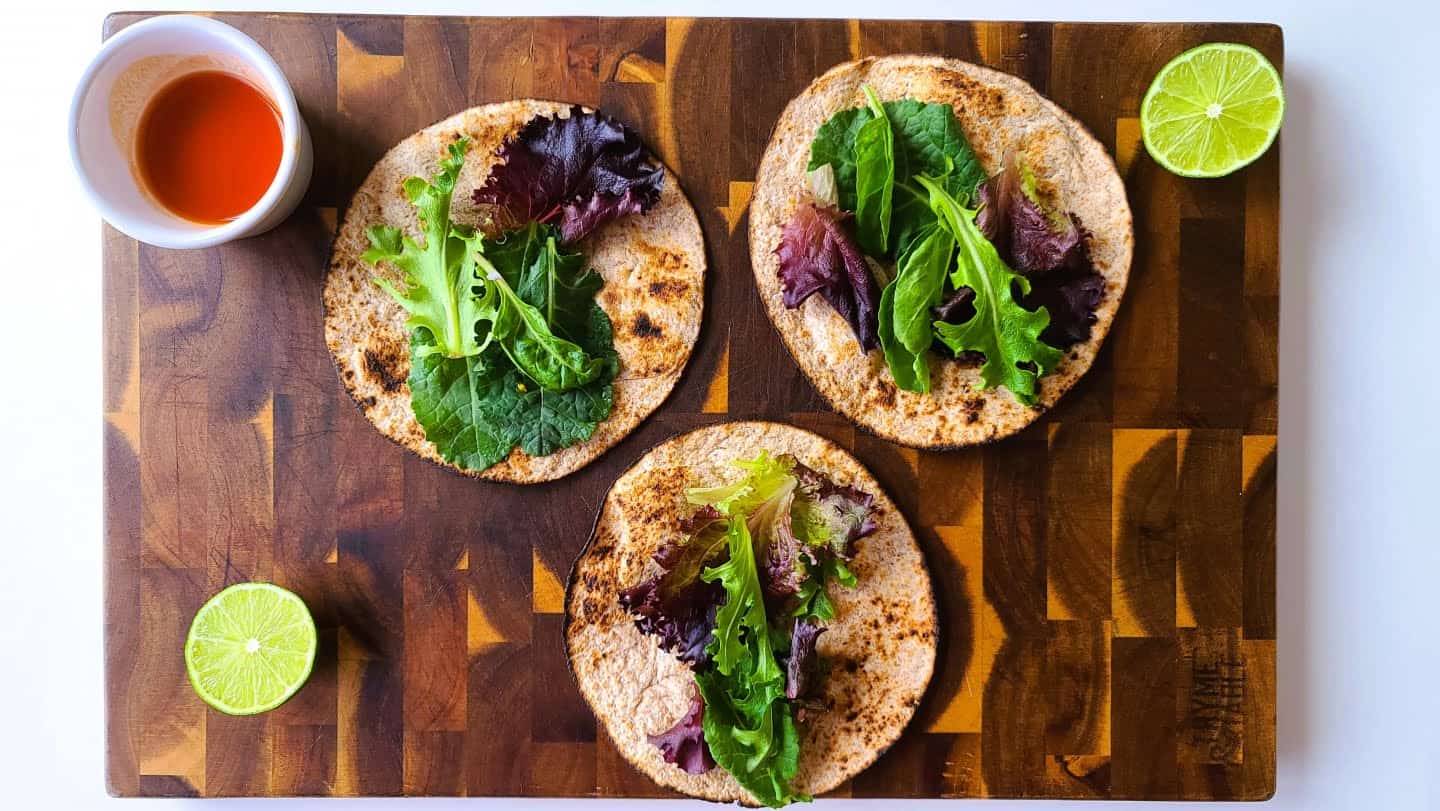 toasted tortillas on a plate and spread a small bunch of green leaves