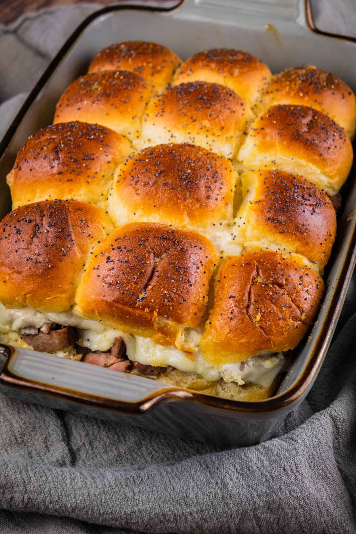 Roast beef sliders in a baking pan  with poppy seeds