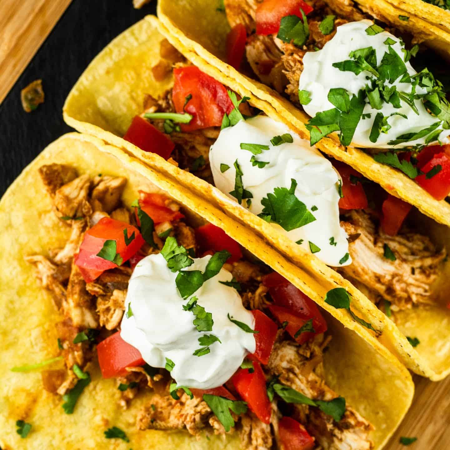 shredded chicken tacos with sour cream and cilantro tomatoes on top