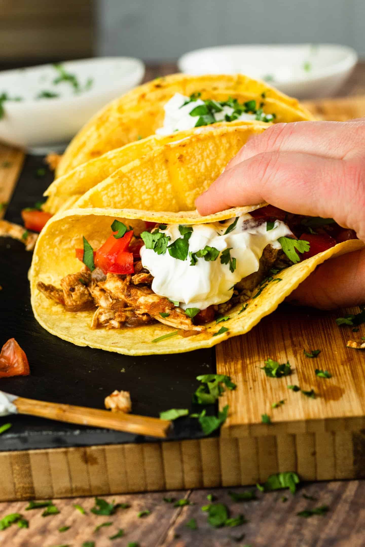 shredded chicken tacos with sour cream and cilantro tomatoes on top