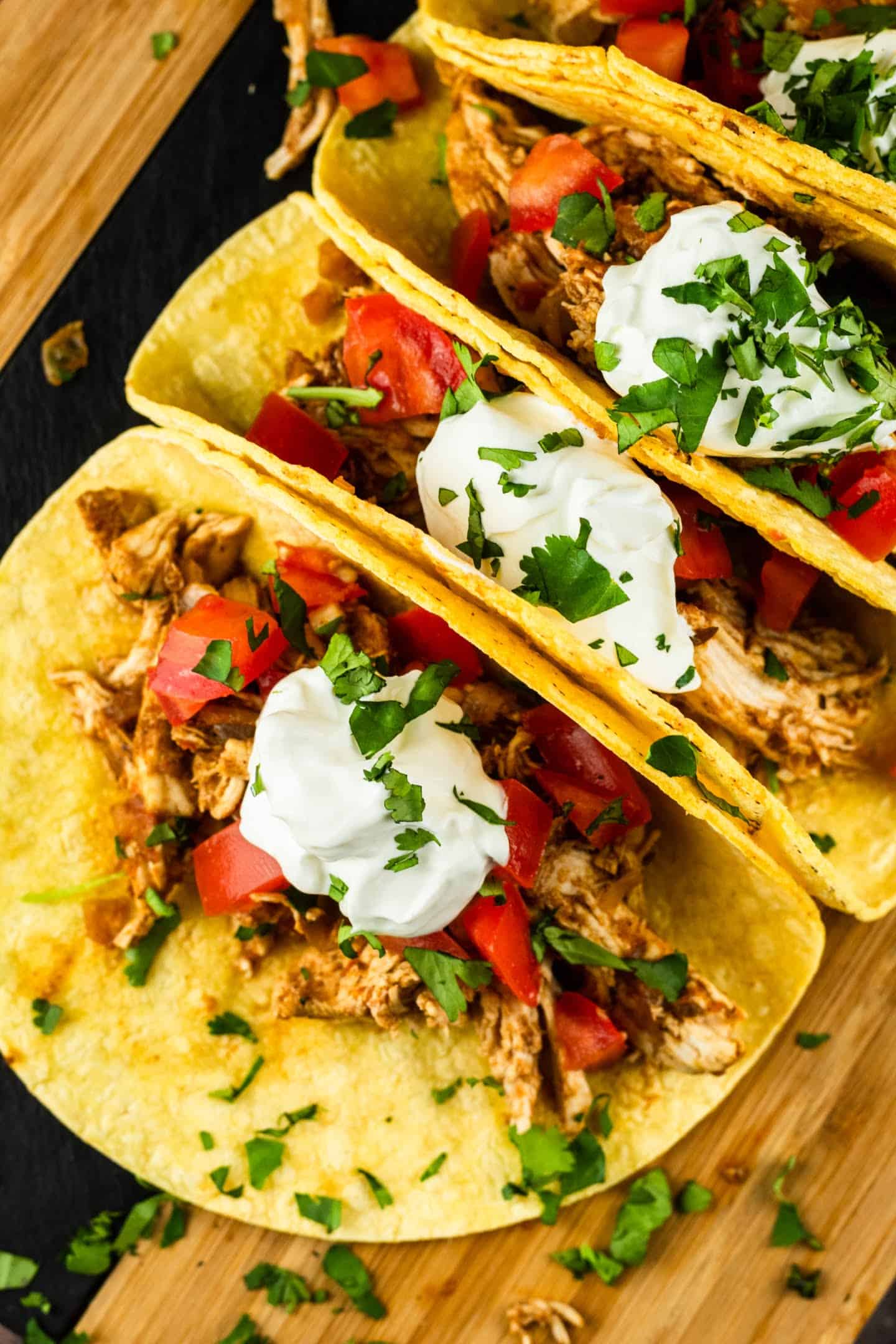 shredded chicken tacos with sour cream and cilantro tomatoes on top