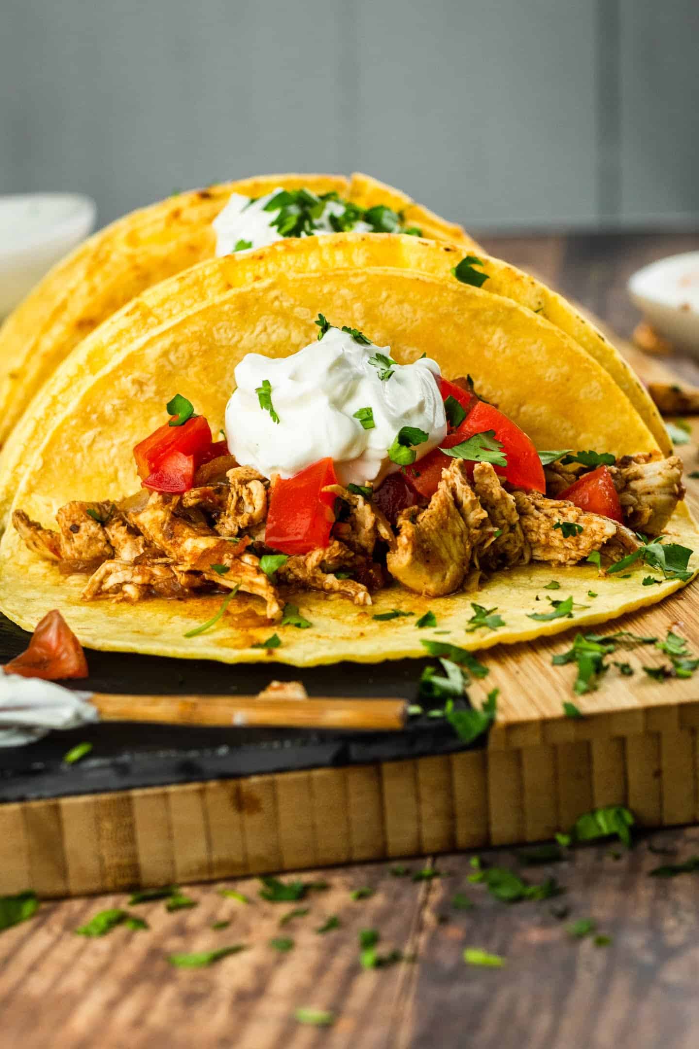 shredded chicken tacos with sour cream and cilantro tomatoes on top