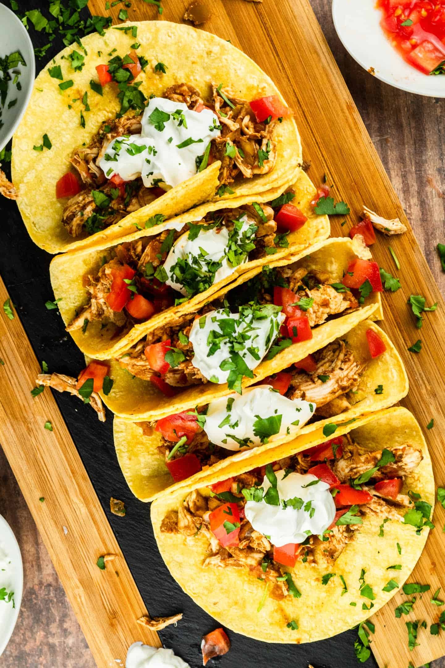 shredded chicken tacos with sour cream and cilantro tomatoes on top
