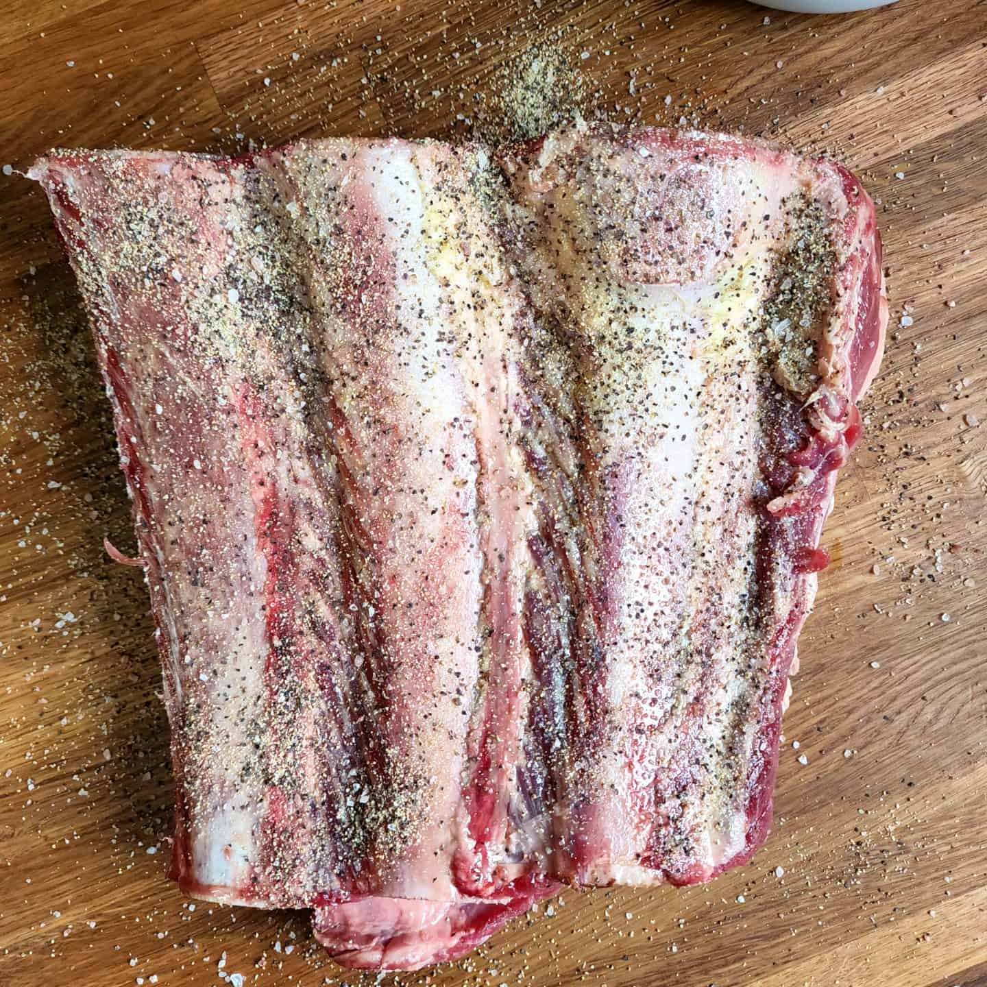 Season beef plate ribs with kosher salt, coarse black pepper, and garlic powder.