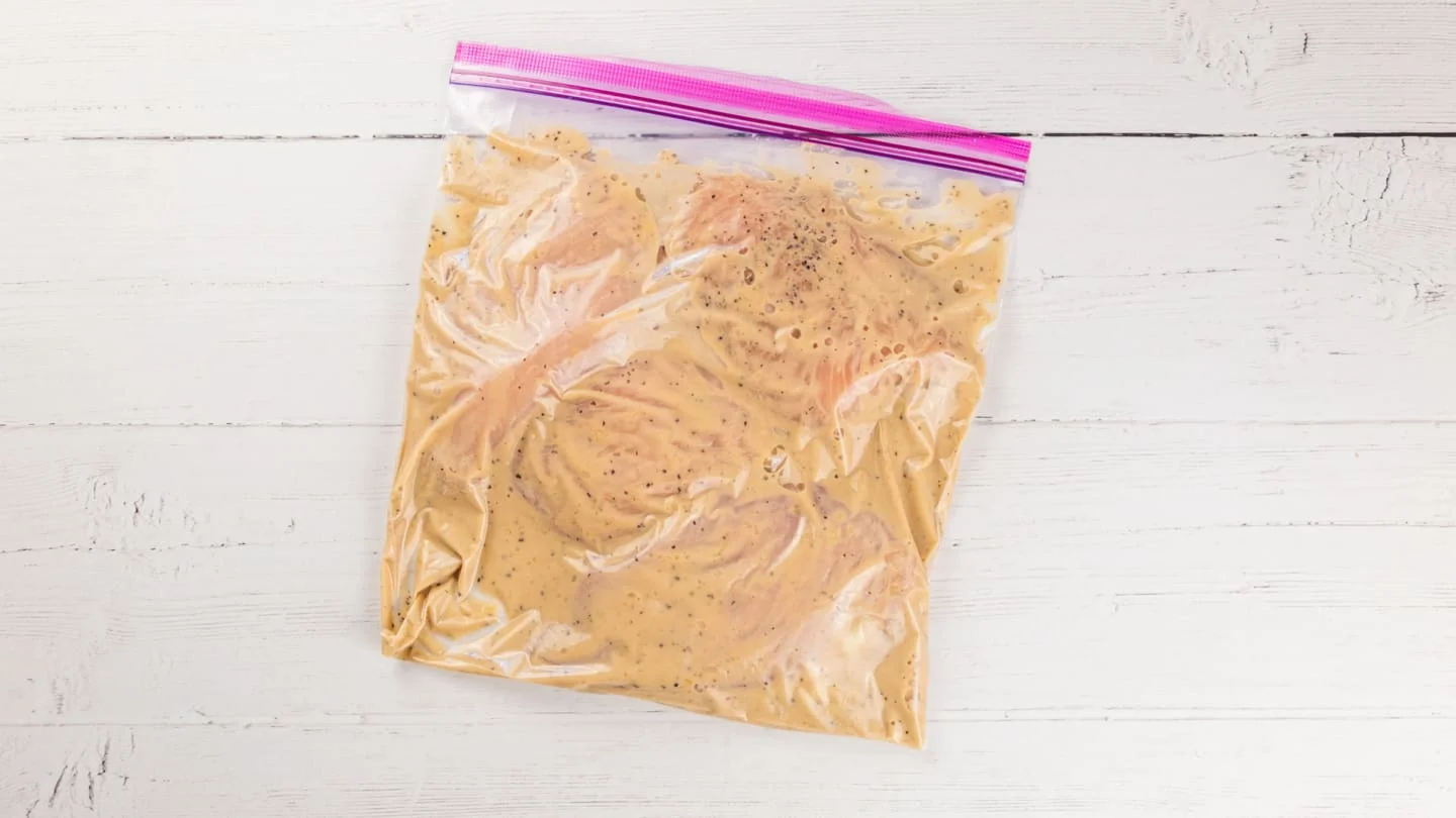 Pouring the marinade in the freezer bag with chicken